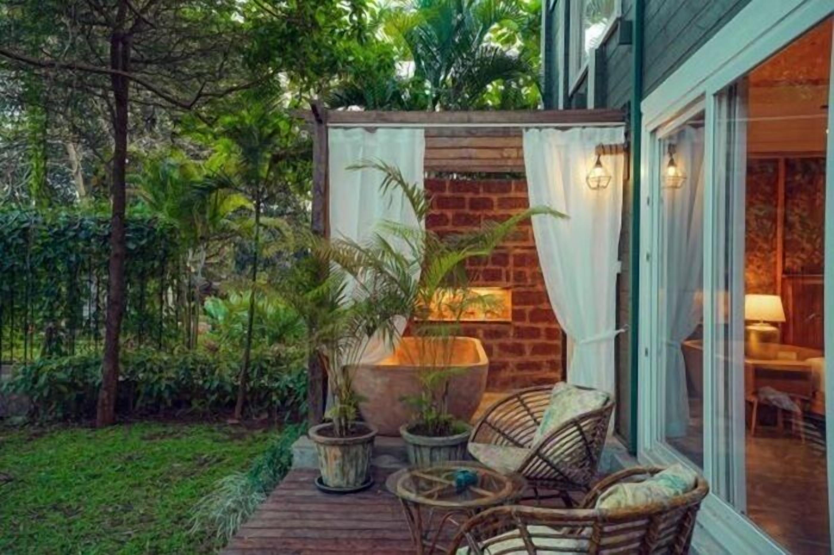 A patio with wicker furniture, potted plants, and a brick wall.