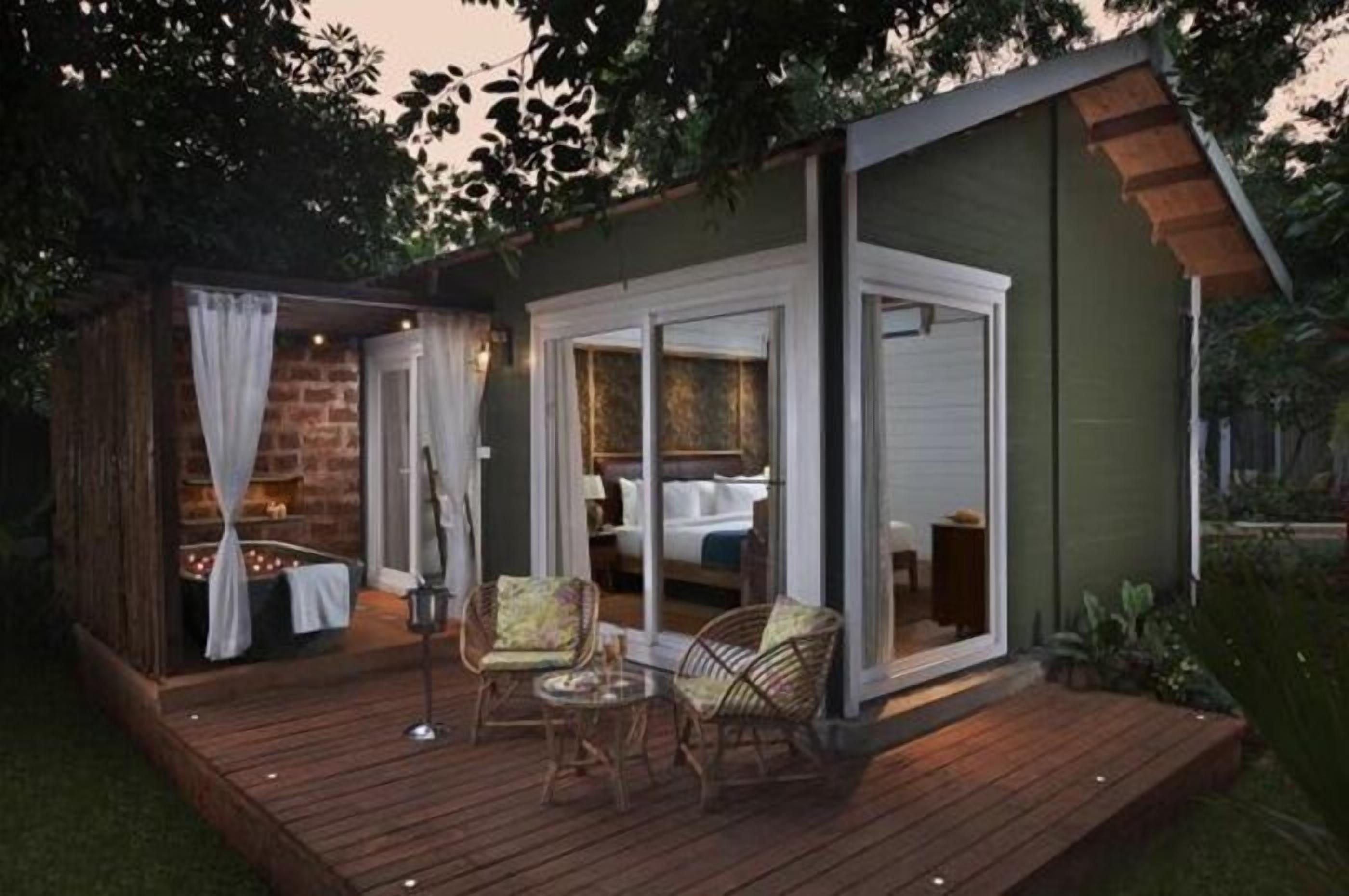 A wooden deck with outdoor seating and a glass door leading to a room.