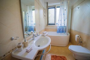 Kombinasi shower/bathtub, pengering rambut, kloset, dan handuk