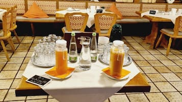A restaurant setting with tables set for dining, featuring clear glassware and bottles of beverages.