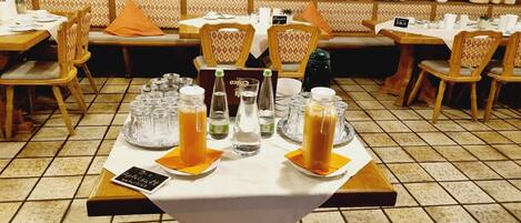 A restaurant setting with tables set for dining, featuring clear glassware and bottles of beverages.