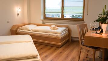 Ein Schlafzimmer mit einem hölzernen Bett, einem kleinen Tisch mit Flasche und Gläsern sowie einem Fenster mit Blick.