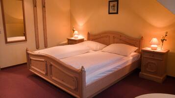 A bedroom with a wooden bed, two bedside tables with lamps, a mirror, and a framed picture on the wall.