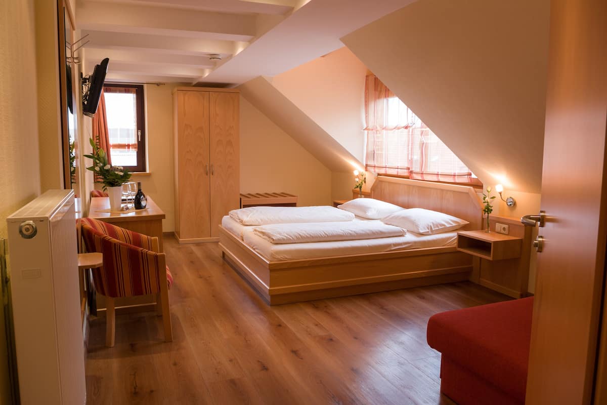 Un dormitorio con cama de madera, un escritorio, una silla y una ventana con cortinas.