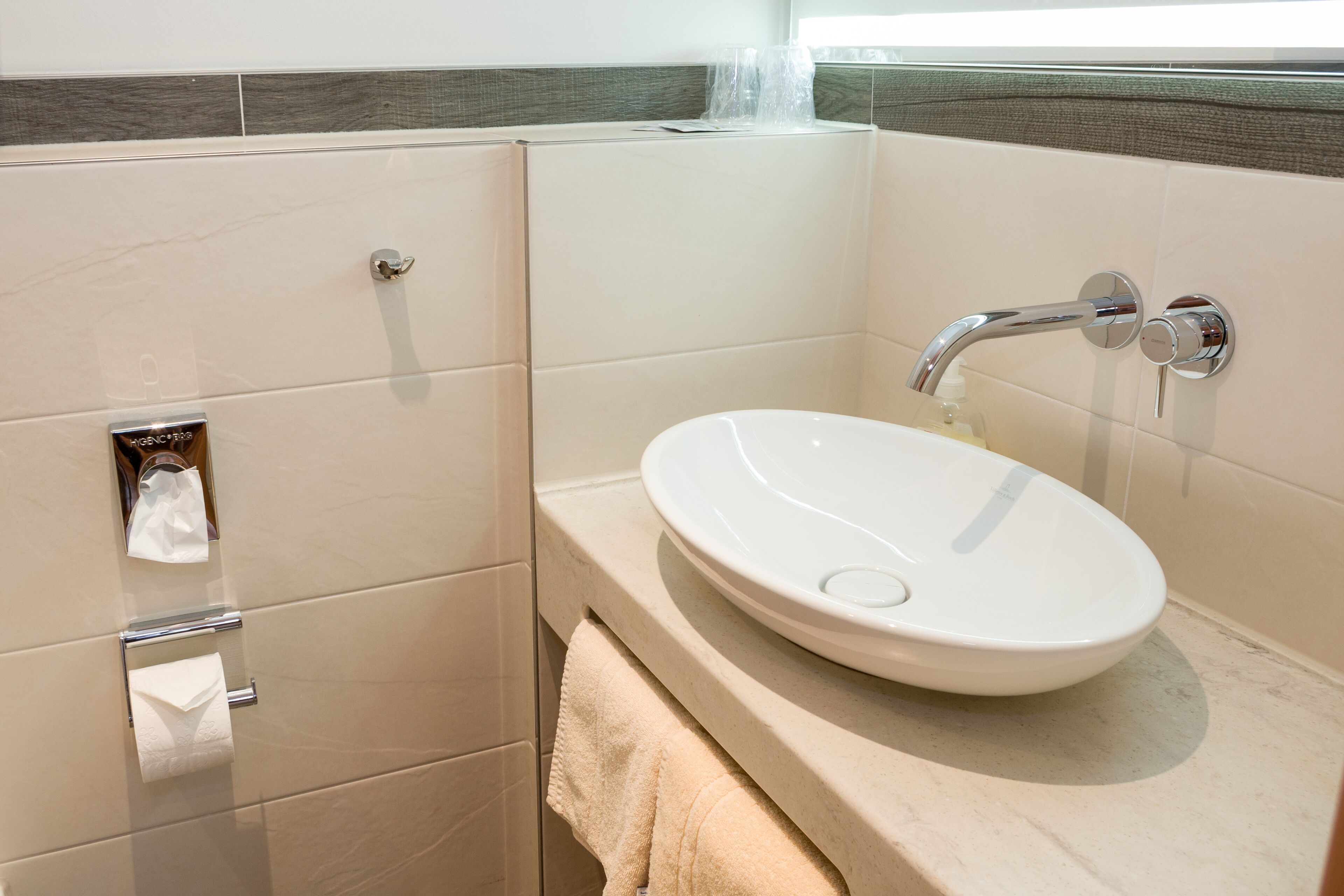 Ein Badezimmer mit weißem Waschbecken, chromfarbenem Wasserhahn und Handtuchhalter.