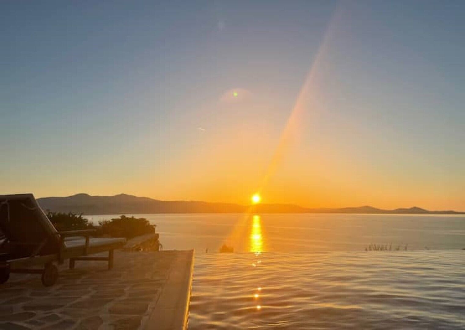Um pôr do sol sobre águas calmas, sob um céu claro.