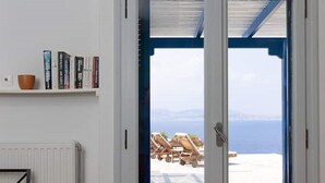A room with a white door leading to a balcony with a view of the sea and beach chairs. - Elanora Villa (Stelida)