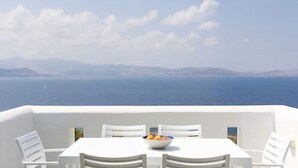 A white table and chairs on a balcony with a view of the sea and distant mountains. - Elanora Villa (Stelida)