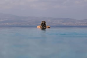 A person relaxing in a clear blue infinity pool with a mountainous backdrop.