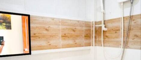 A bathroom with white tiles, a wooden panel wall, a mirror, and a shower with a handheld showerhead.