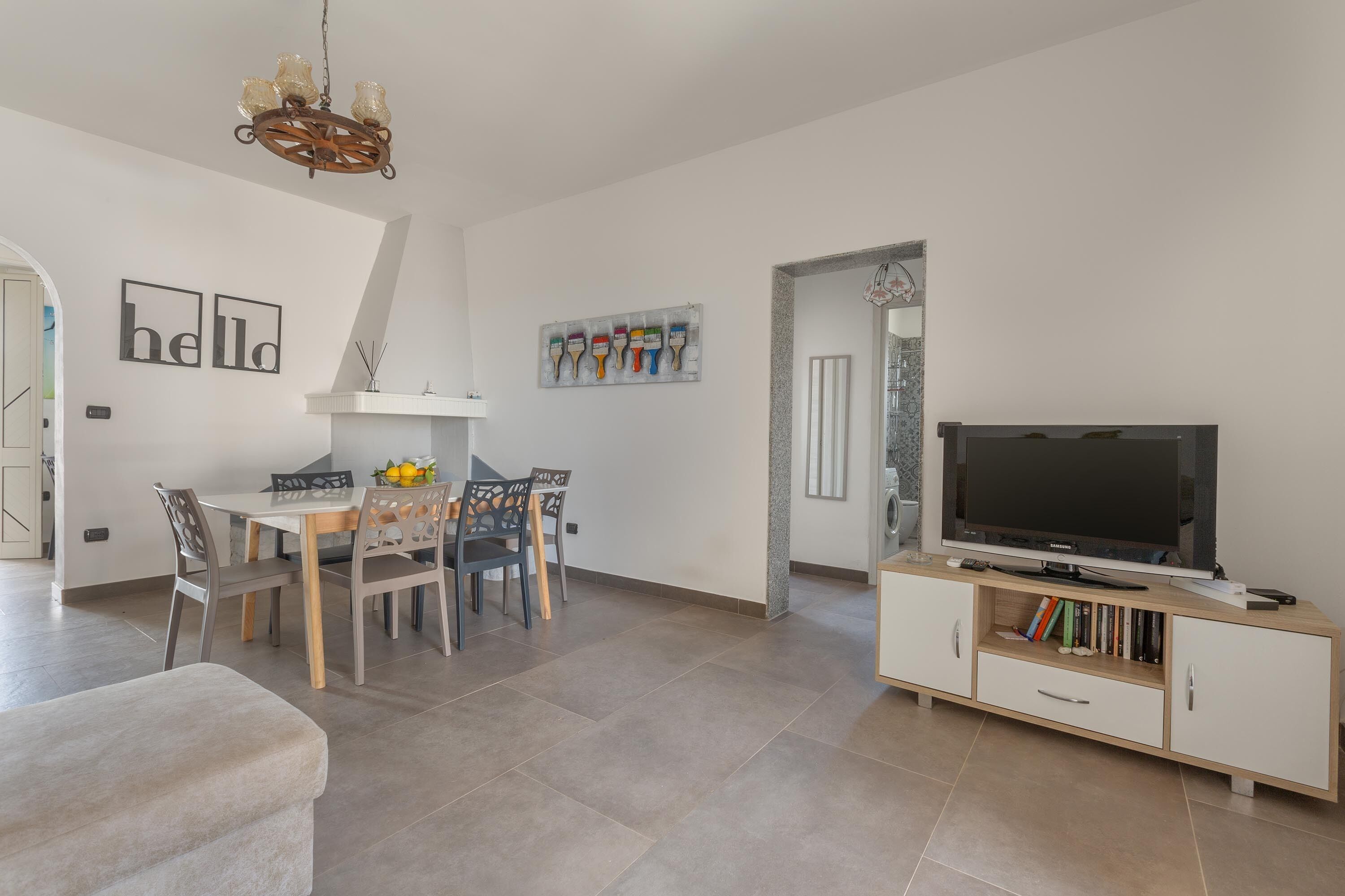 Ein modernes Wohnzimmer mit Essbereich, einem Fernseher auf einem Holzkabinett und einer Kristallleuchtre.
