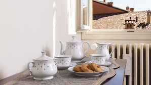Une pièce avec une fenêtre, un radiateur et une table sur laquelle sont disposés un service à thé et des biscuits.