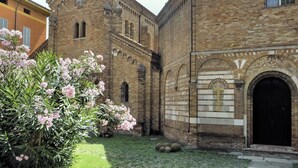 Un bâtiment historique doté d’une cour intérieure, avec une grande entrée en arc de cercle et une croix sur la façade.