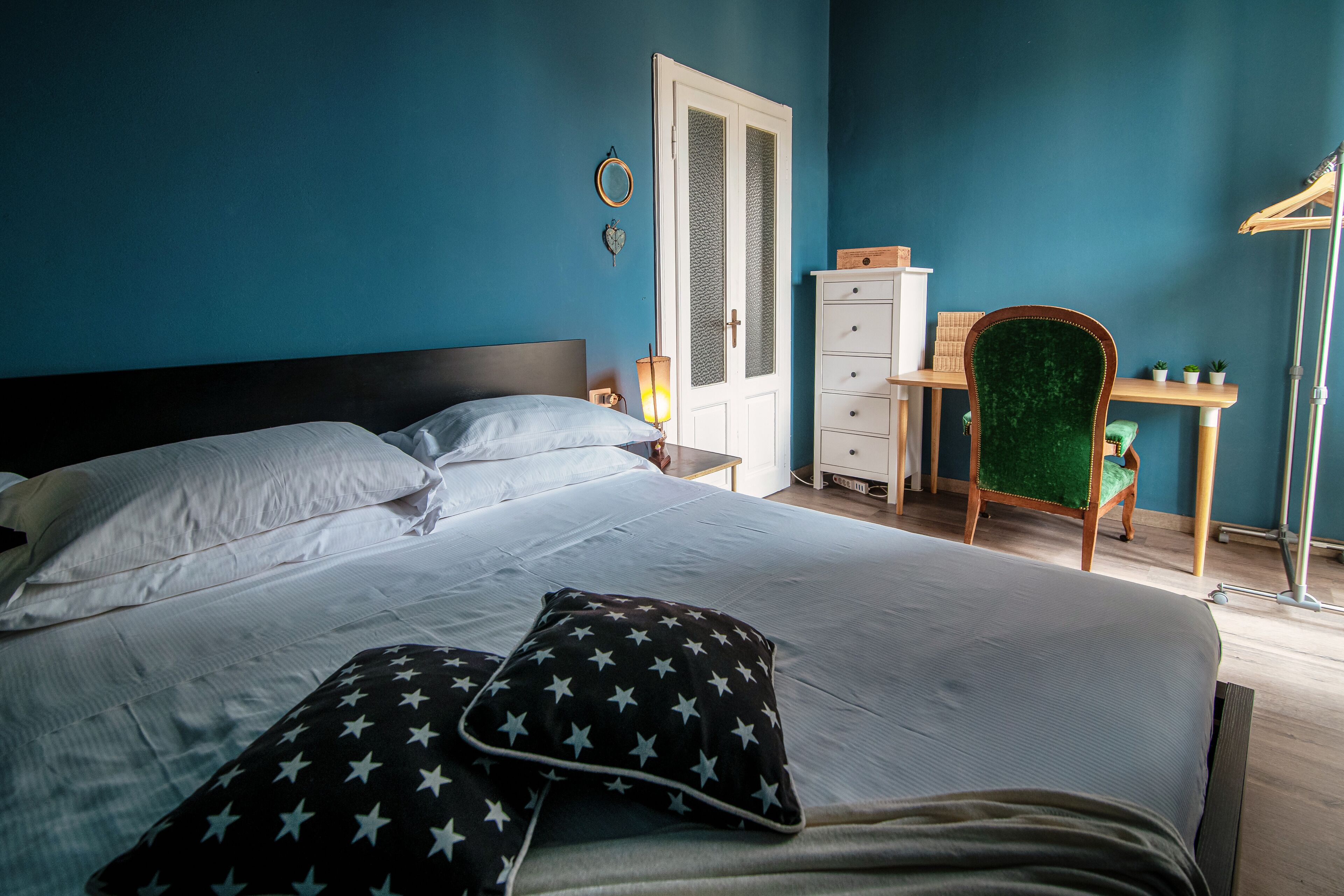 A bedroom with a bed, pillows, a dresser, a chair, and a desk.