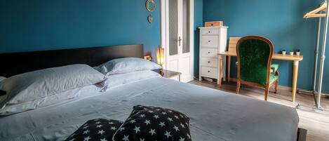 A bedroom with a bed, pillows, a dresser, a chair, and a desk.