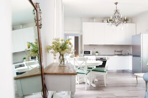A modern kitchen with white cabinets, a wooden countertop, and a chandelier. - Glamour (Como)