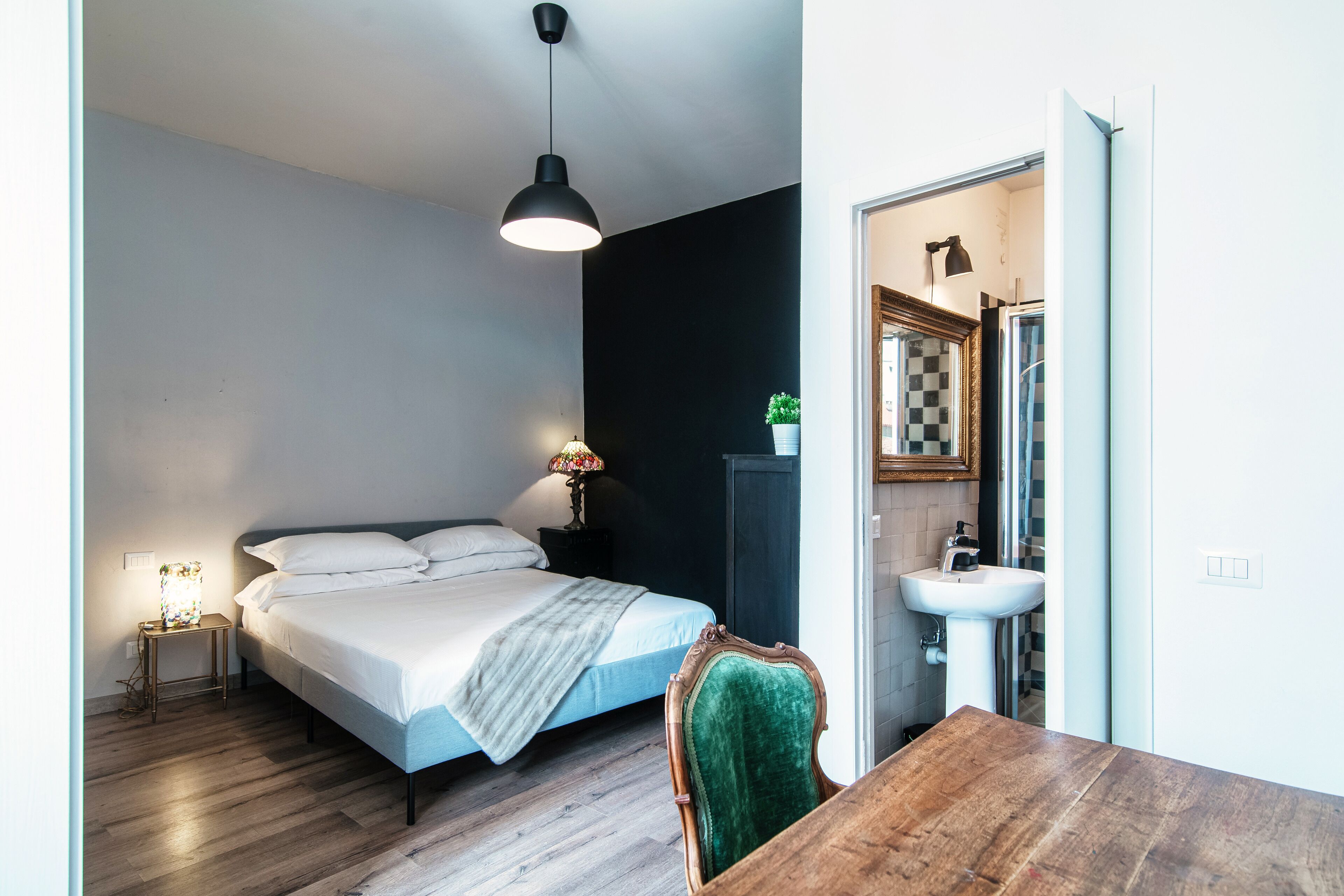 Een slaapkamer met een bed, een bedlamp en een houten tafeltje.