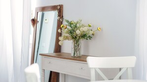 A white desk with a vase of flowers, a mirror, and a white chair in a room with light-colored walls. - Glamour (Como)