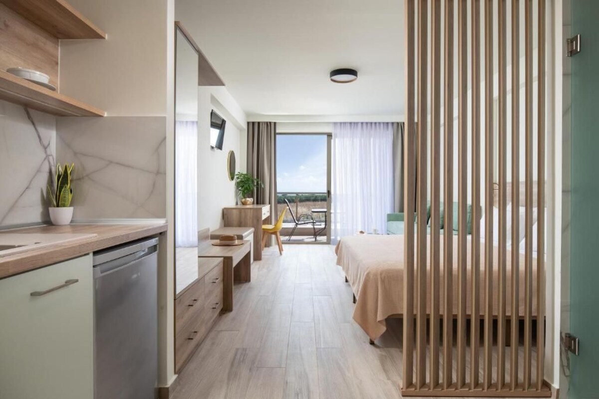 Une chambre d’hôtel moderne dotée d’un coin cuisine, d’une table à manger, d’un lit et offrant une vue sur la ville.