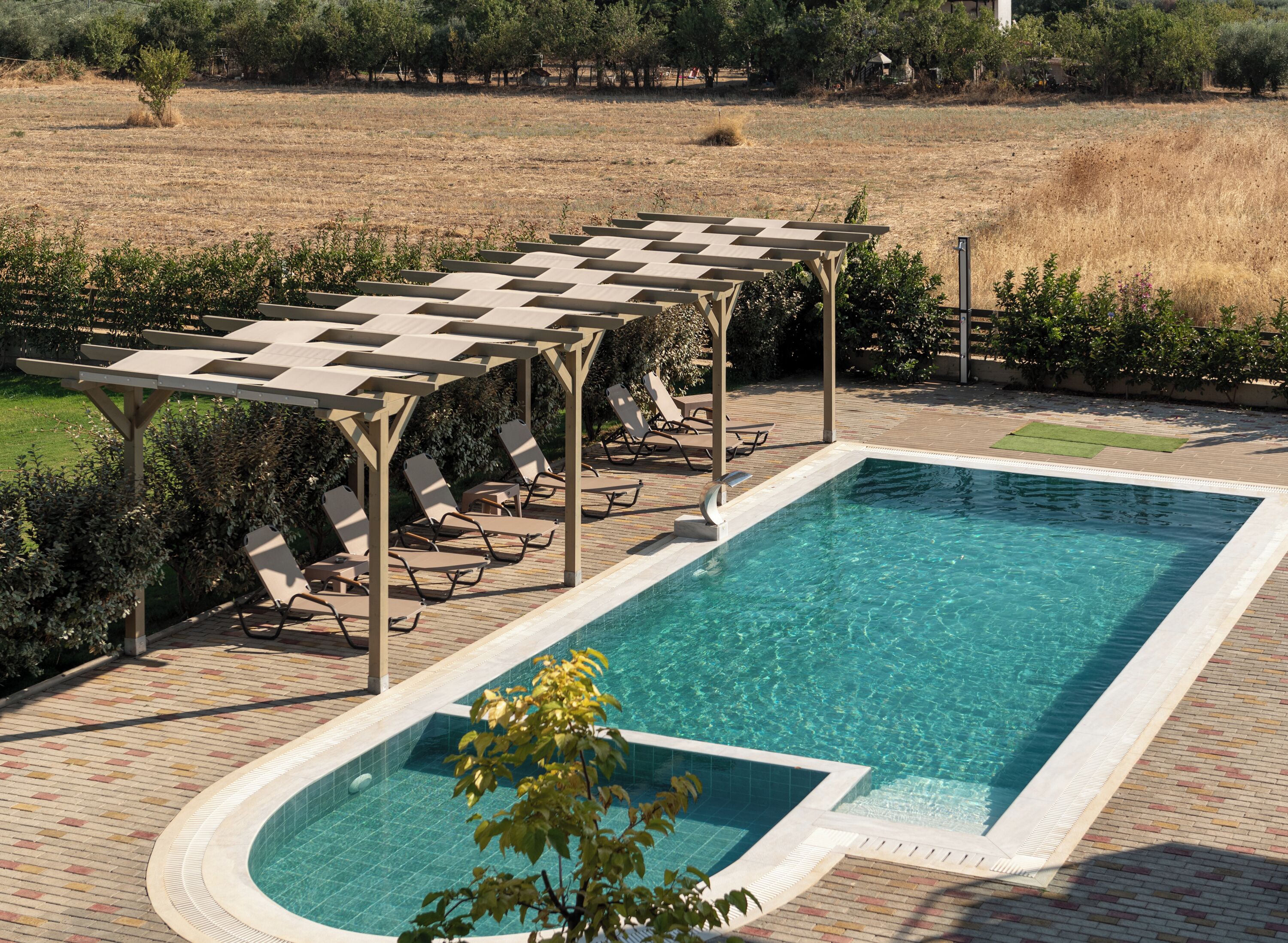 A rectangular swimming pool with a checkered sunshade structure and lounge chairs.