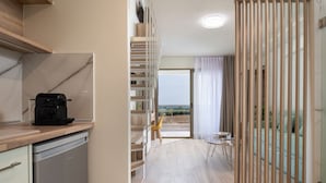 Eine moderne Küche mit Kaffeemaschine, Holzböden und Blick ins Freie.
