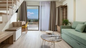Ein modernes Wohnzimmer mit Treppe, einem grünen Sofa, einem runden Couchtisch und Blick durch ein großes Fenster.