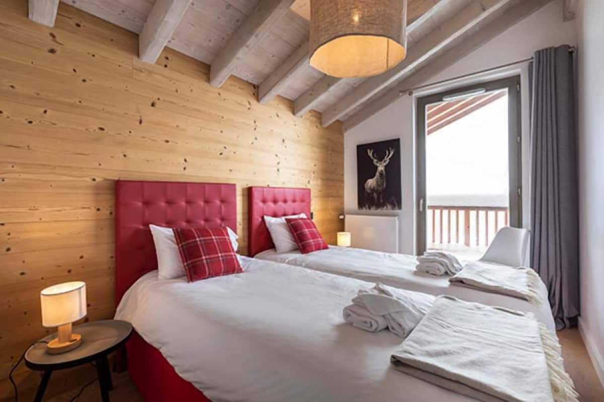 Et hotelværelse med to senge, en trævæg, et stort vindue og en balkon.
