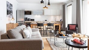 A modern living room with a sofa, coffee table, and dining area. - TERRESENS - Le Hameau de Barthélémy (Montvalezan)
