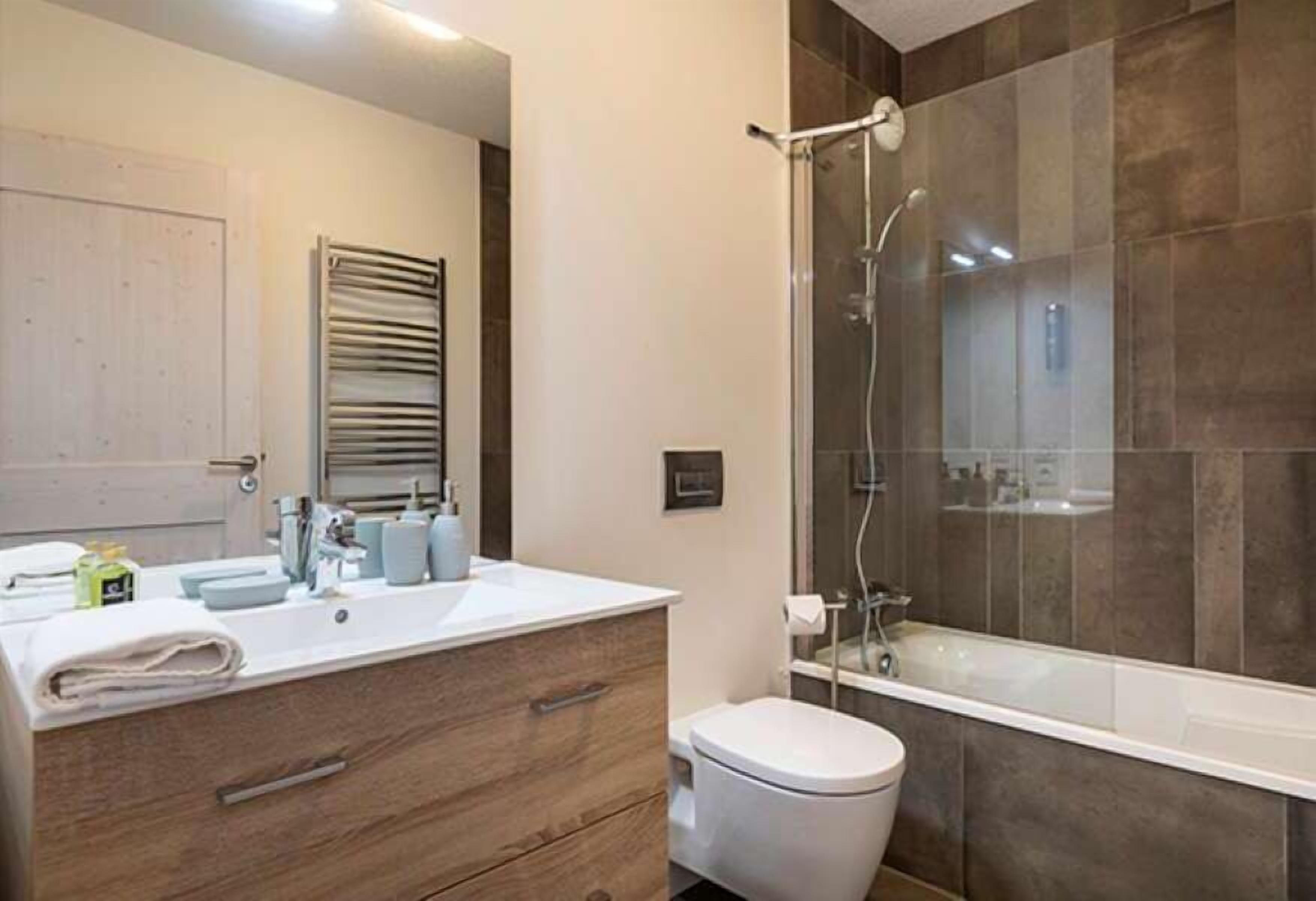 A modern bathroom with a large shower, a toilet, and a vanity with a sink.