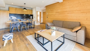 Una cocina moderna con armarios de madera, un comedor con sillas, un sofá y una mesa de centro.