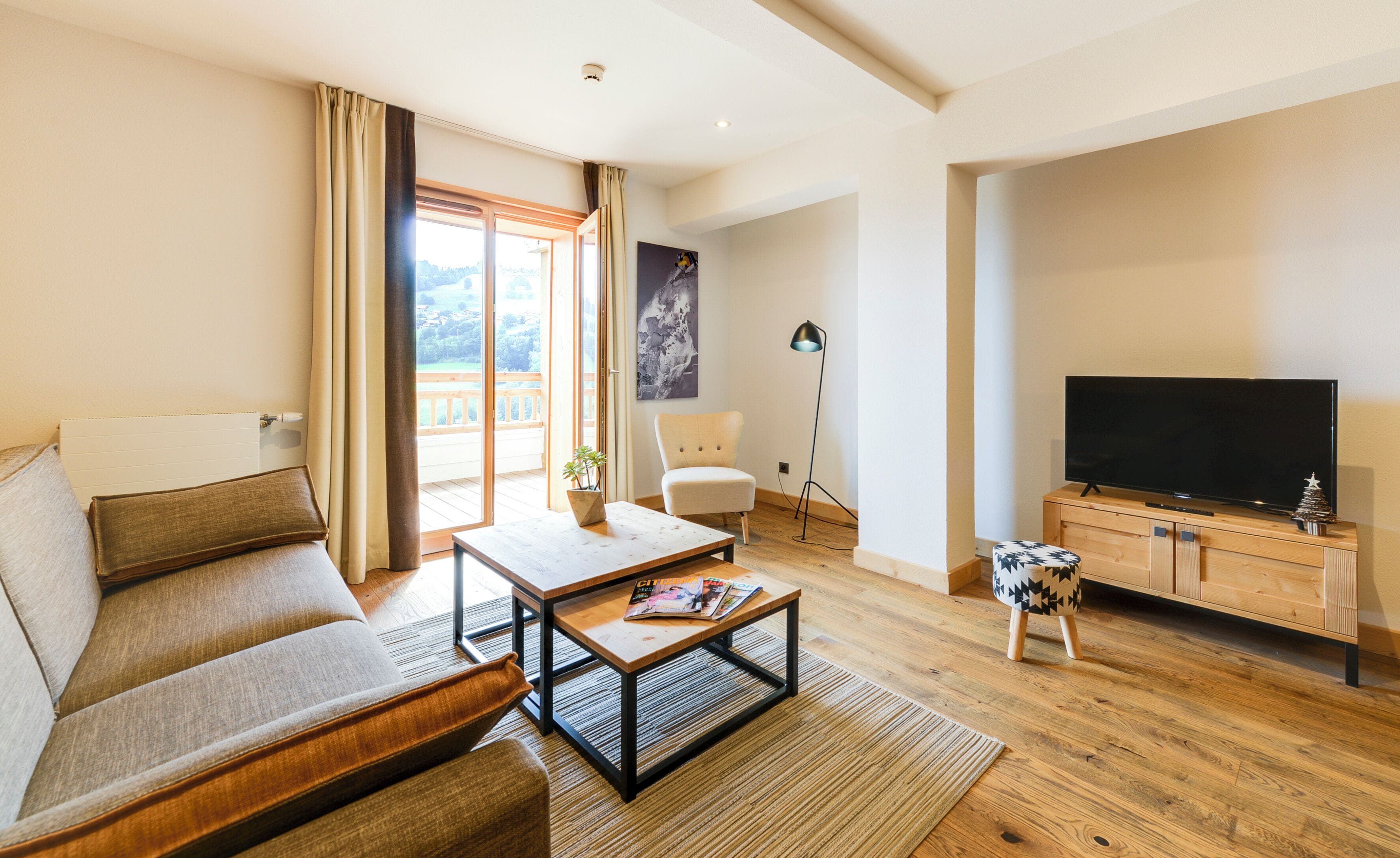 A modern living room with a sofa, coffee table, TV, and a balcony with curtains.
