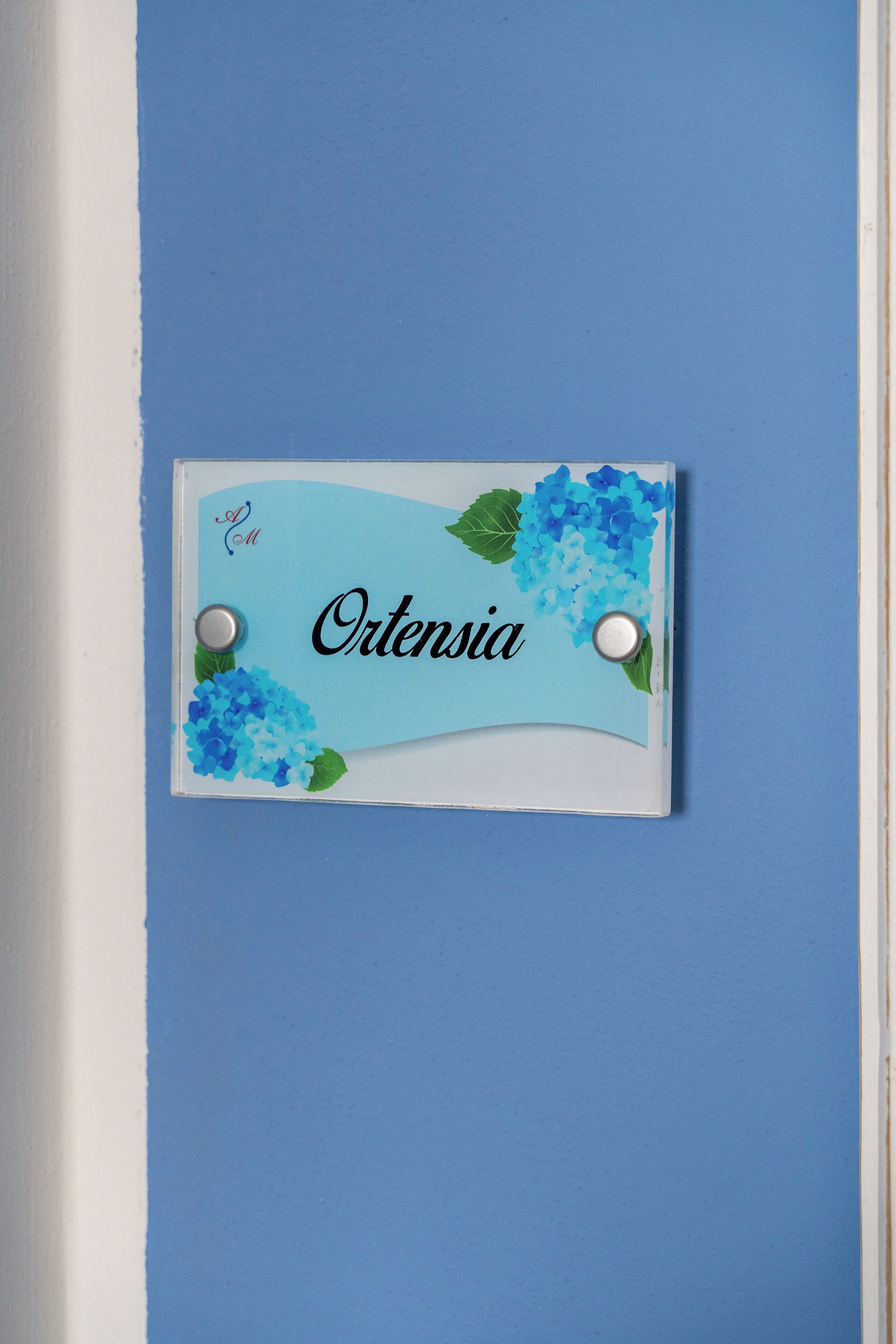 A nameplate with the name "Ortenzia" on a blue wall.