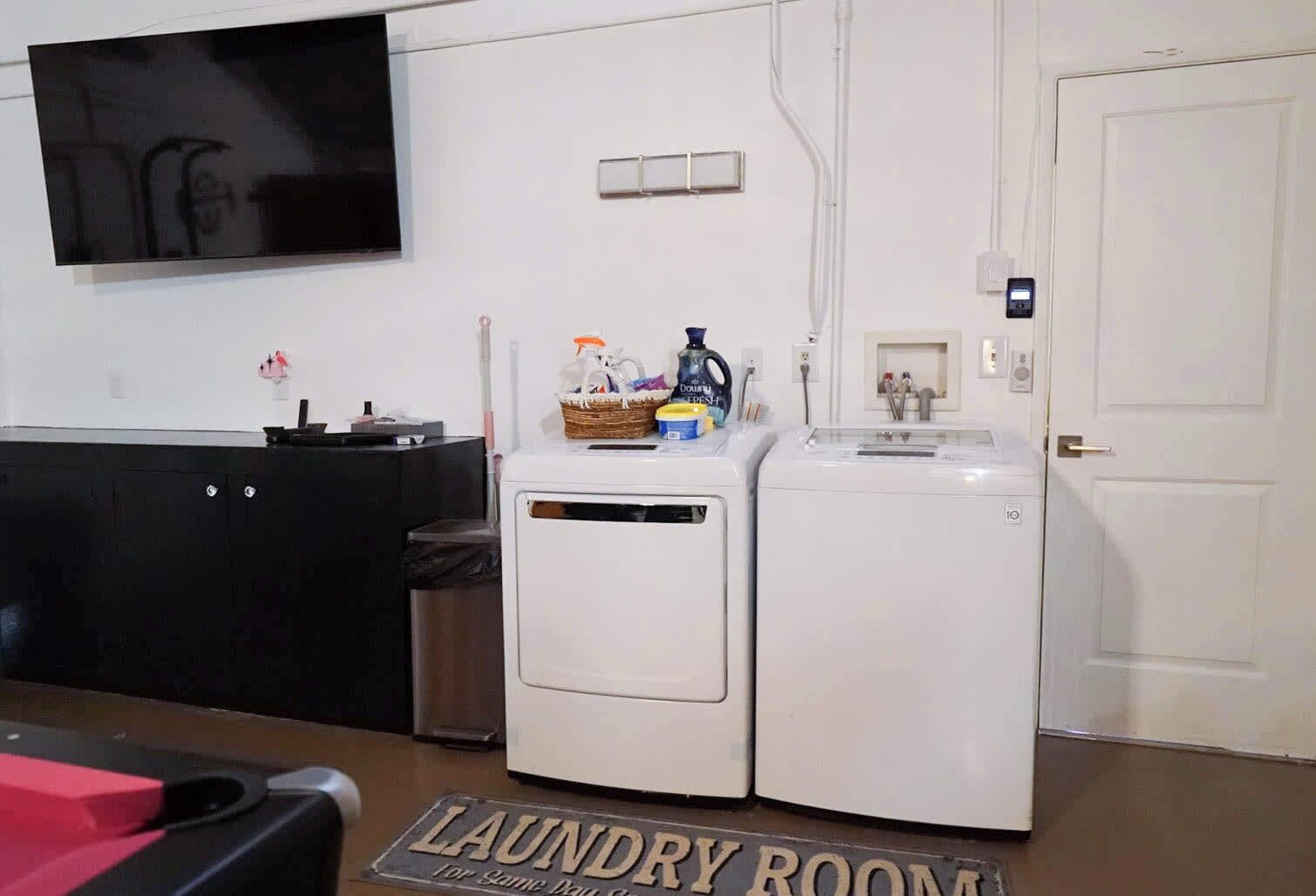 Een wasserette met twee wasmachines, een wastafel, een aan de muur bevestigde televisie en een deur met slot.