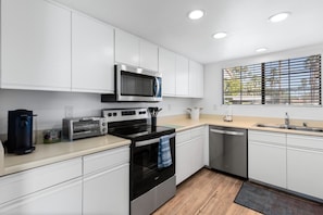 A modern kitchen with white cabinetry, a microwave, a toaster, an oven, and a dishwasher.