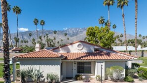 A single-story house with a red-tiled roof, a small porch, and a well-maintained lawn. - Palm Springs Oasis: Gated Condo w/ Pool & Hot Tub (Palm Springs)