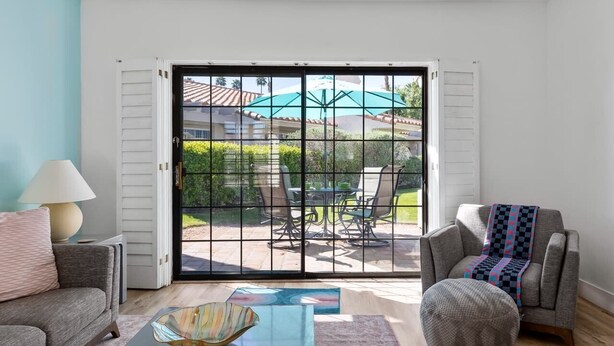 A living room with a sliding glass door leading to an outdoor patio area. - Palm Springs Oasis: Gated Condo w/ Pool & Hot Tub (Palm Springs)