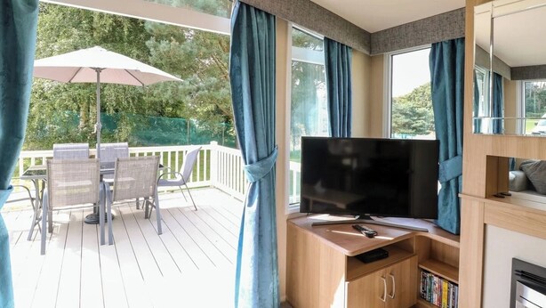 Ein Balkon mit Fernseher, Sitzgelegenheit und Bücherregal.
