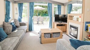 Ein gemütliches Wohnzimmer mit Sofa, Fernseher, Kamin und Essbereich mit Gartenmöbeln.