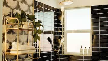 A bathroom with a shower, a window, and a towel rack with plants.