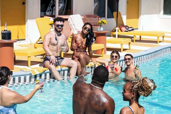 Un espace piscine avec des chaises longues et un bar au bord de la piscine.