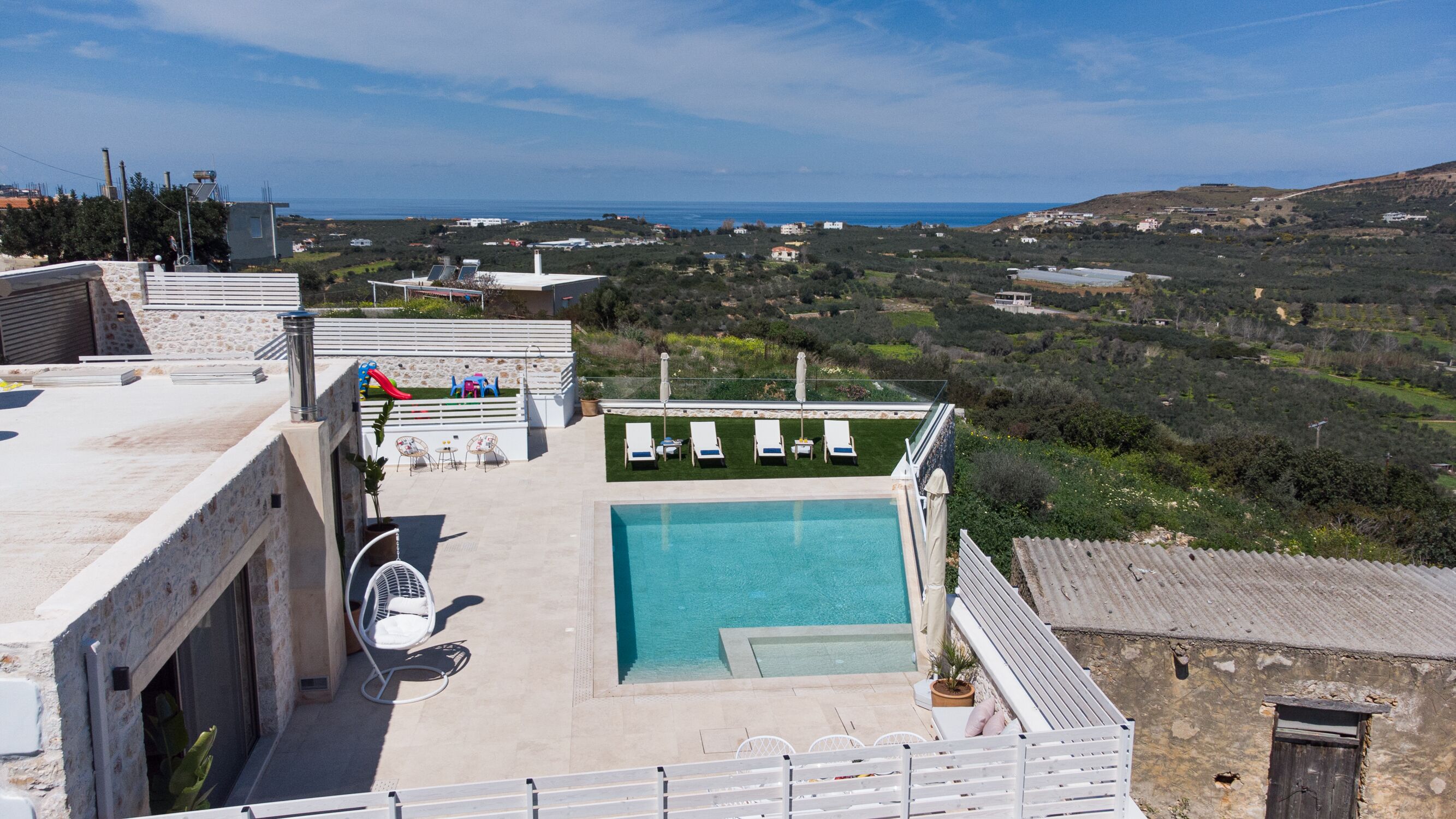 Una piscina sul tetto con lettini e uno scivolo, affacciata su un paesaggio costiero.