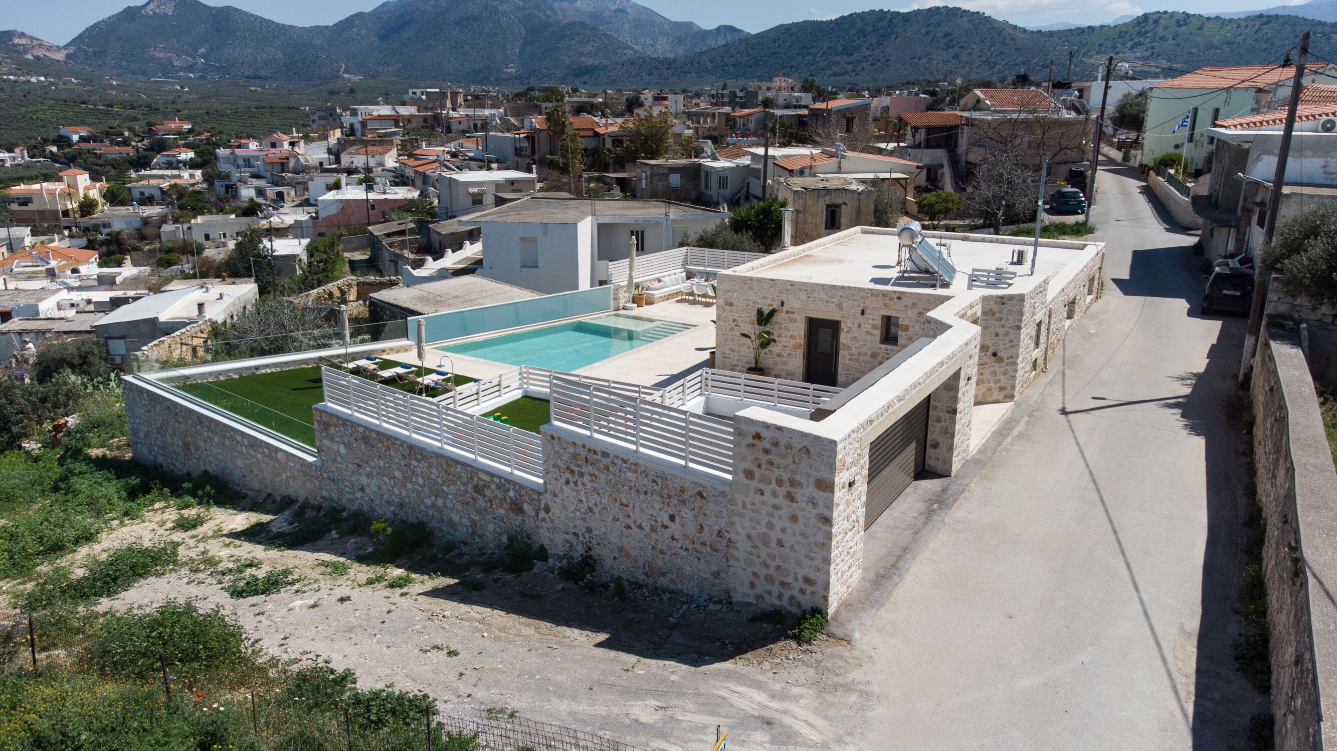 Área residencial com edifícios de pedra, piscina e estrada.