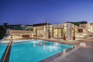 A swimming pool with a stone exterior and modern outdoor seating area. - Villa Valentina, 2bedrooms relaxing retreat, w/private pool, playground and view (Roumeli)