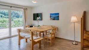 Un comedor con una mesa y sillas de madera, una lámpara de pie y dos cuadros en la pared.