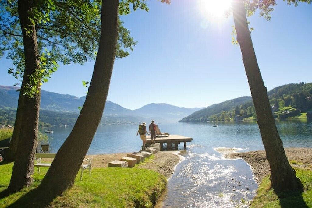 A lakeside view with a wooden dock and steps leading to a bench.