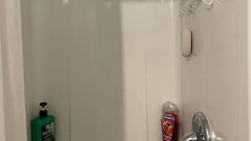A bathroom with a shower, a soap dispenser, and a soap bottle.