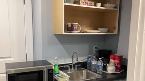 A compact kitchen with a stainless steel microwave, a sink, and a refrigerator. - Valley Studio Private Suite (Abbotsford)