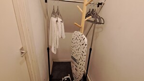 Ein kleiner Waschbereich mit Wäscheständer, Bügeleisen und einem Handtuch an der Wand.