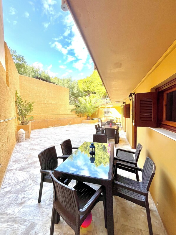 An outdoor patio with a table and chairs, a potted plant, and a view of the sky and trees.