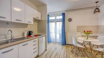 A modern kitchen with white cabinets, a sink, and a dining area with a table and chairs.
